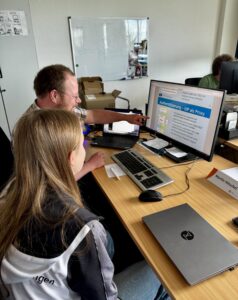 Clara and Martin are discussing something on the computer during their BOGY work placement at DAASI International